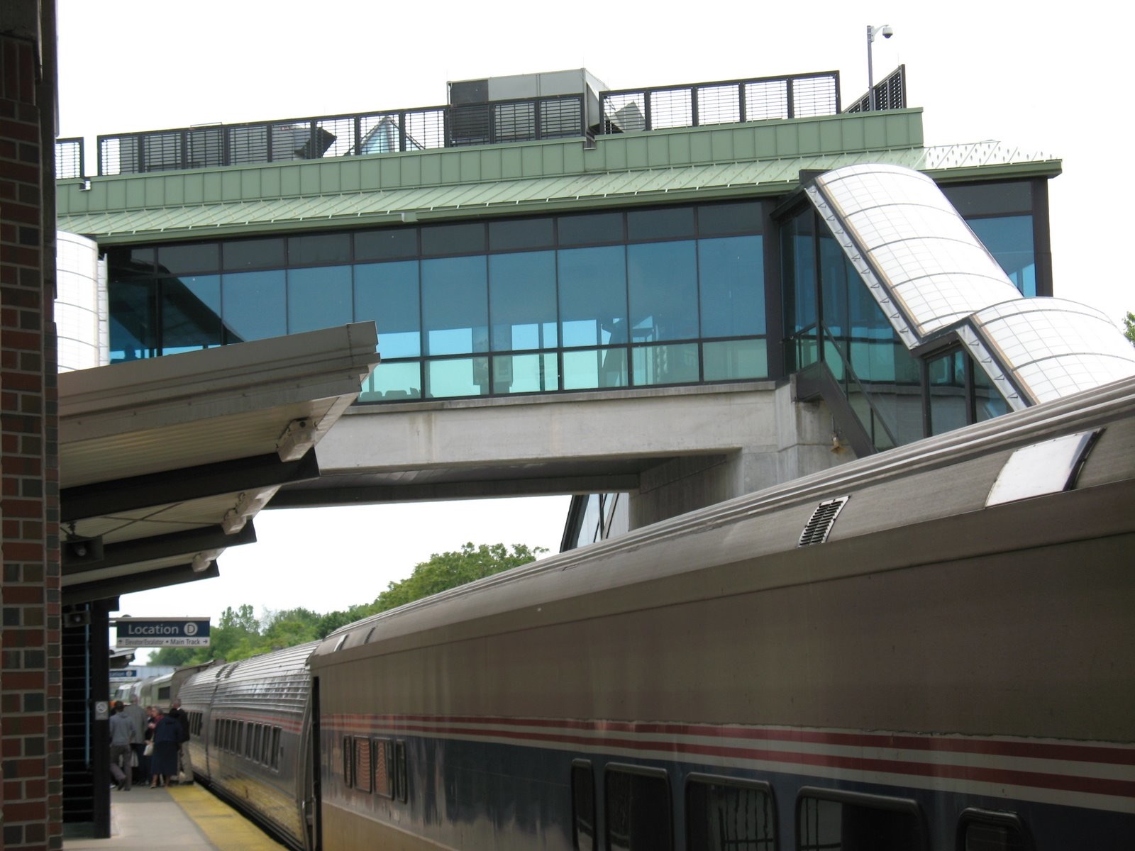 a train traveling by a building and bridge