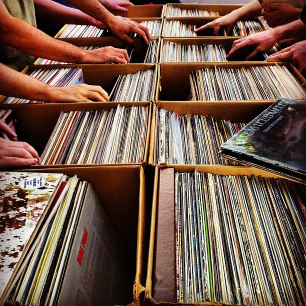 lots of records stacked in their boxes as hands touch them
