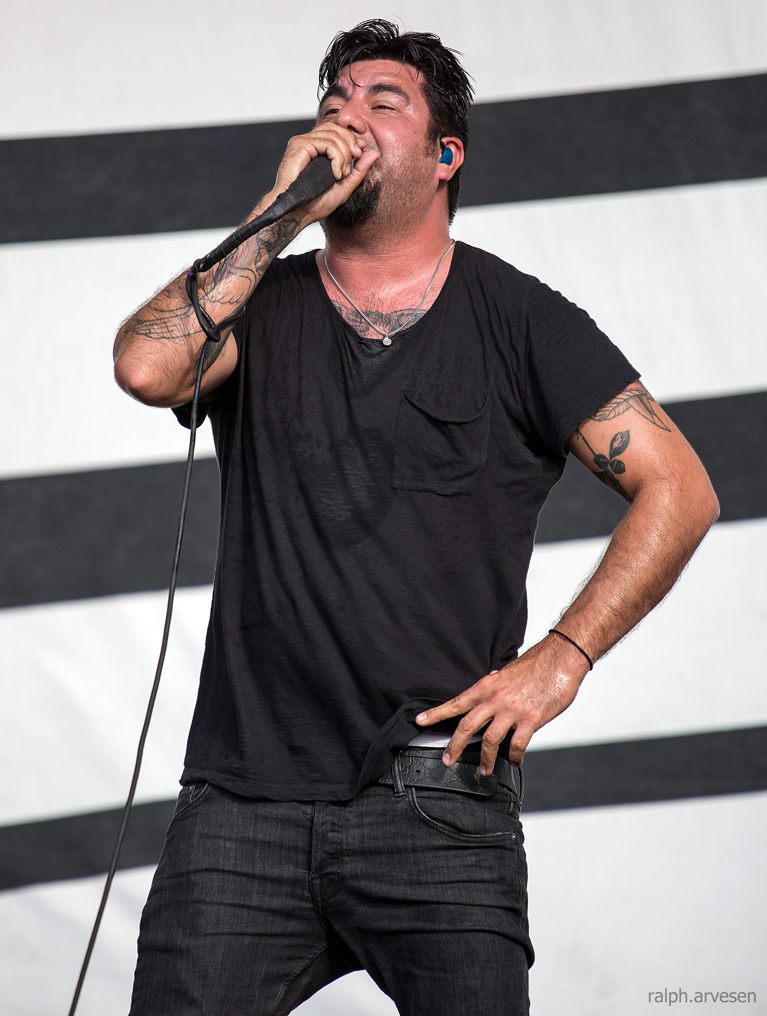 a man wearing a t - shirt singing into a microphone