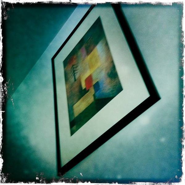 a framed art with multi colored squares hung on a wall