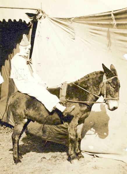 a woman riding on the back of a brown horse next to a tent