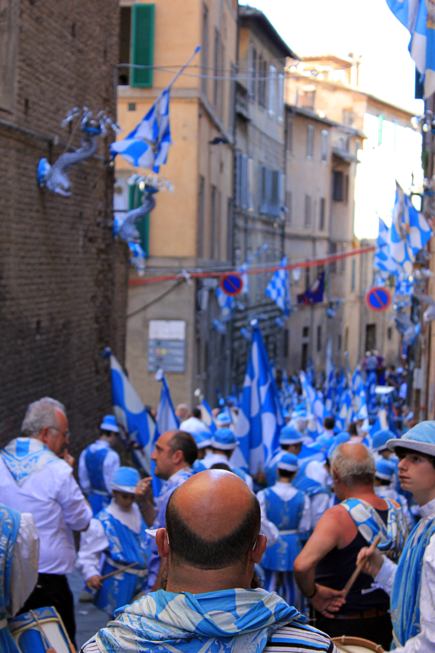 people marching down a city street with blue flags and buildings