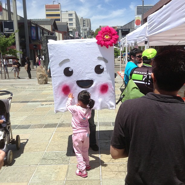 a child in pink walks by a sign with a face