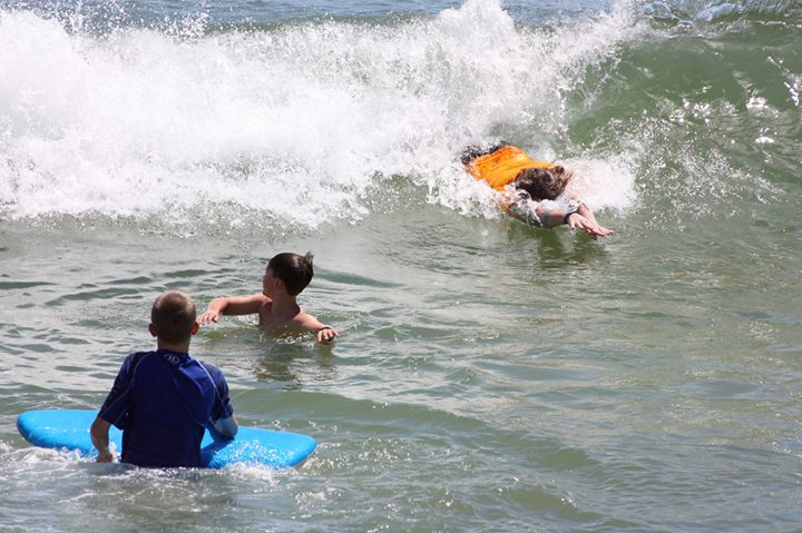 two children on surf boards ride in a wave