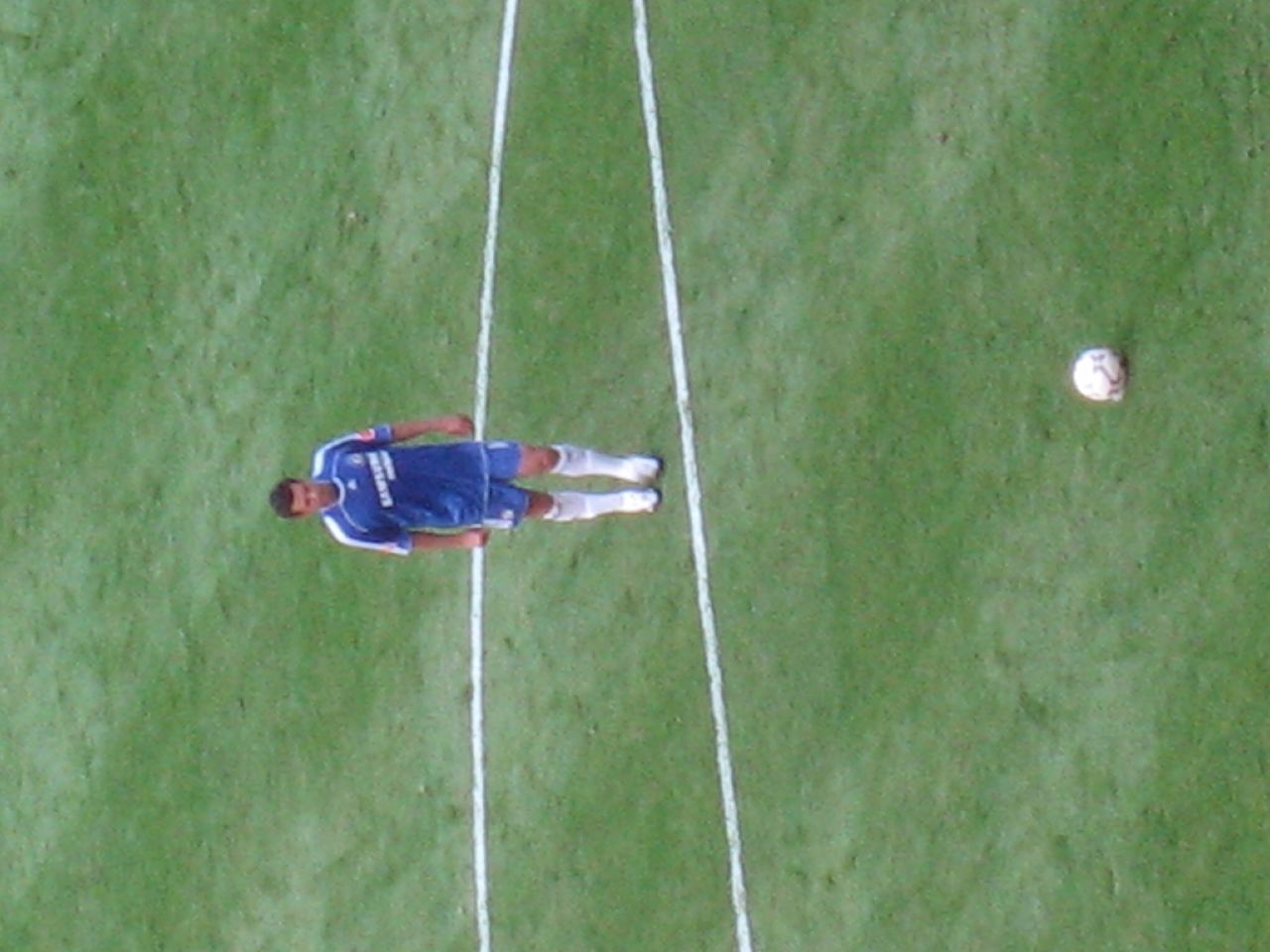 soccer player wearing blue uniform and white socks and looking at ball