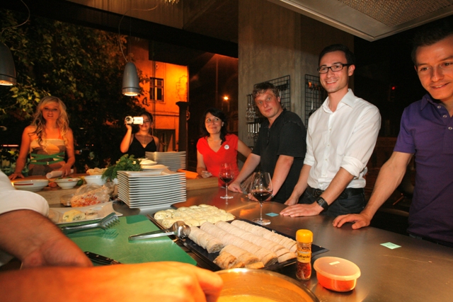 a group of people standing around a kitchen table with food