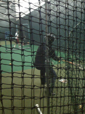 a man playing batting on the field in a batting cage