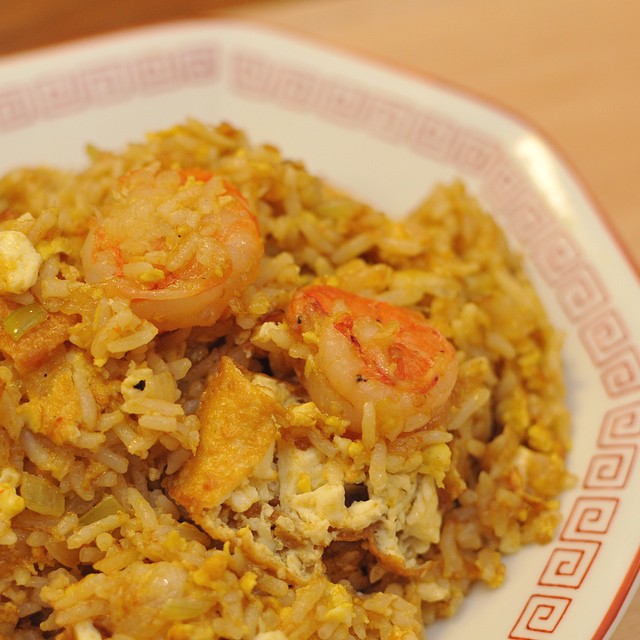 a dish with shrimp and rice on a white and red plate