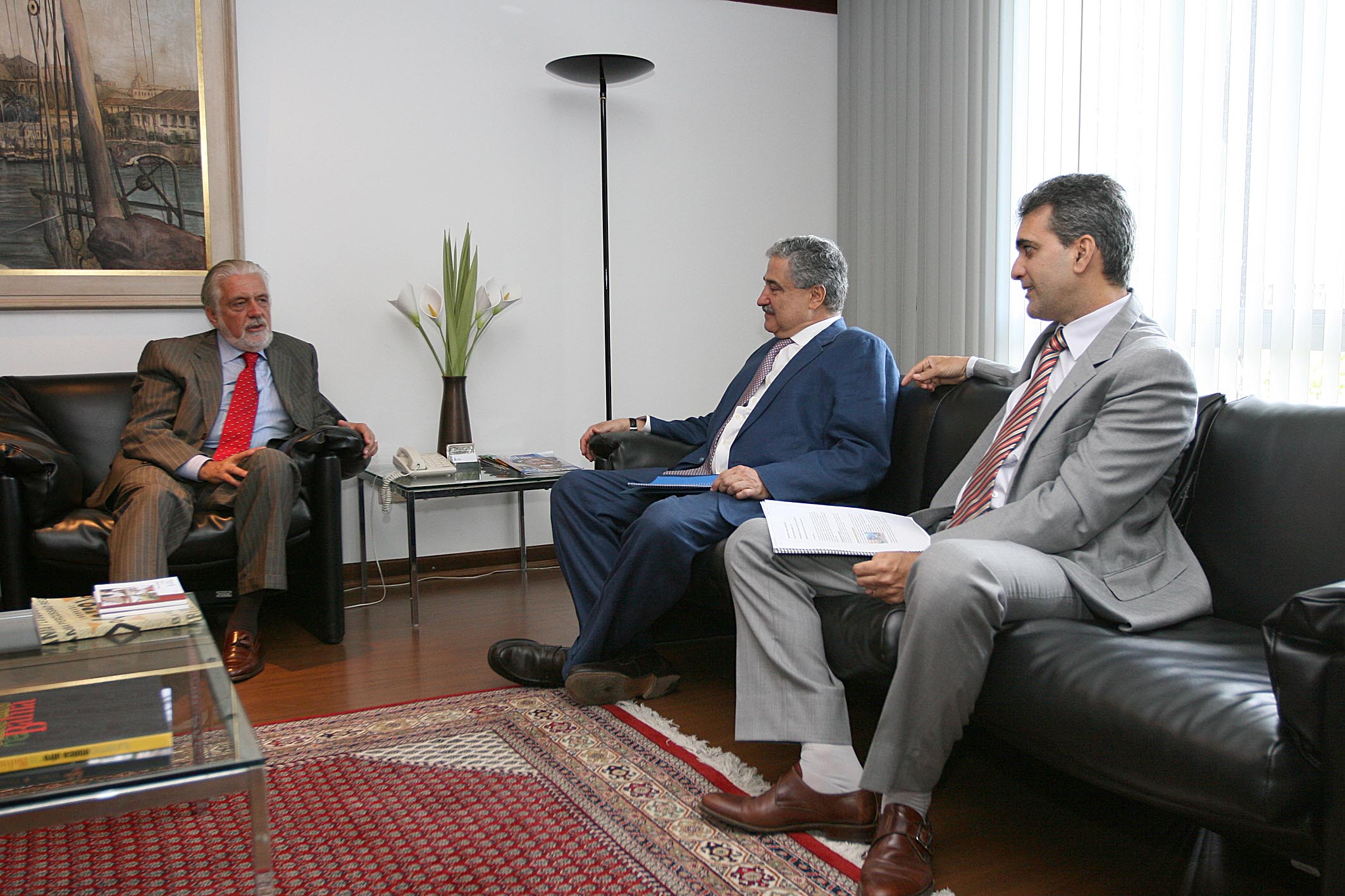 three men in business suits sit in a room