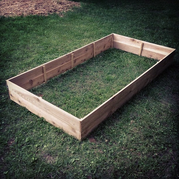 an outdoor garden bed made with boards on grass