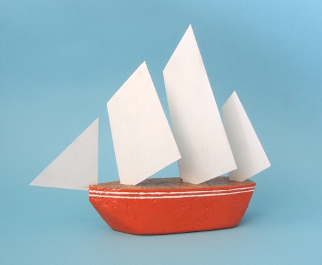 small orange paper boat with sails on blue background