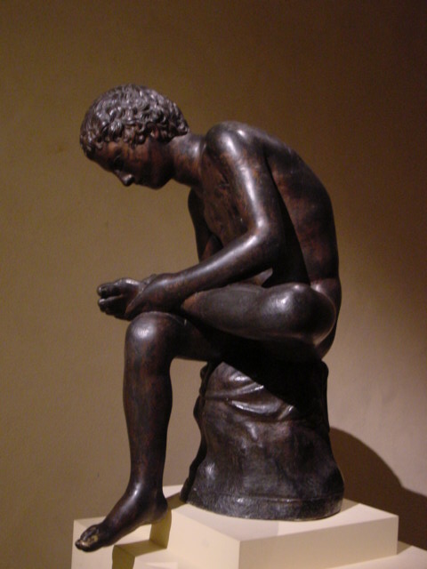 a bronze sculpture of a person with one foot on a stone block