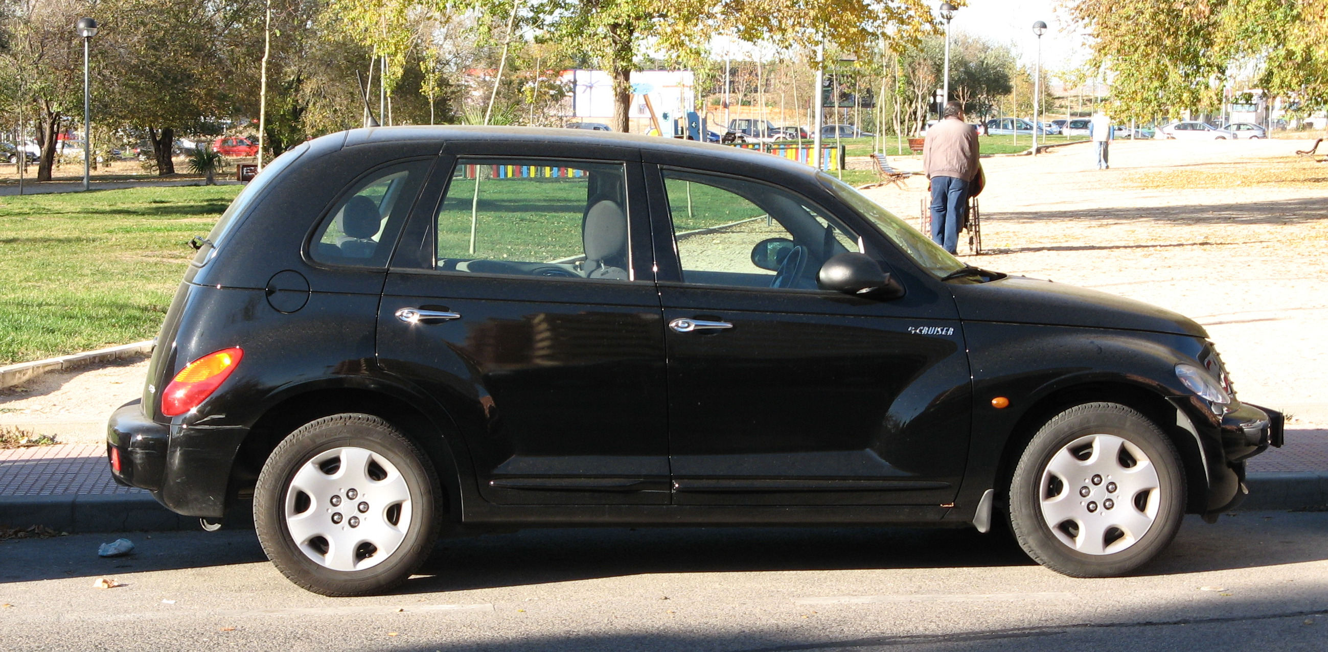 a small black compact car parked on the curb next to a curb