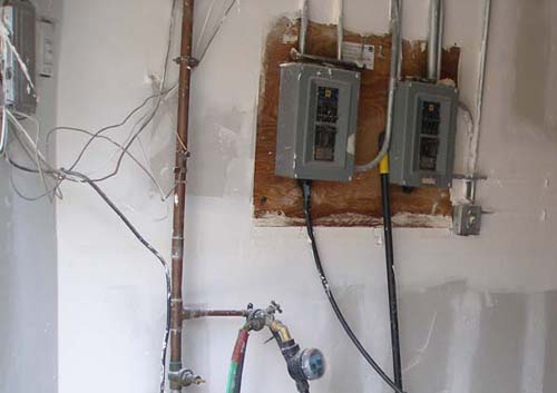an electrical panel and wall mounted meter in the corner of a room