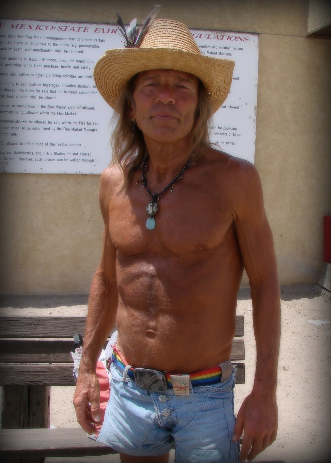 shirtless man wearing a straw hat and celet