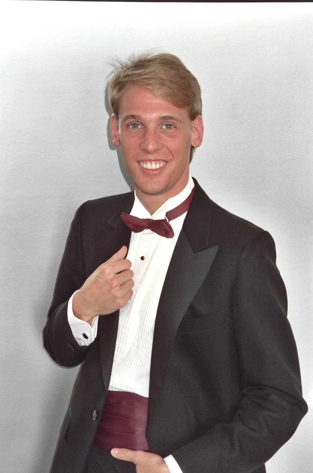 man in tuxedo smiling and pointing finger at shirt