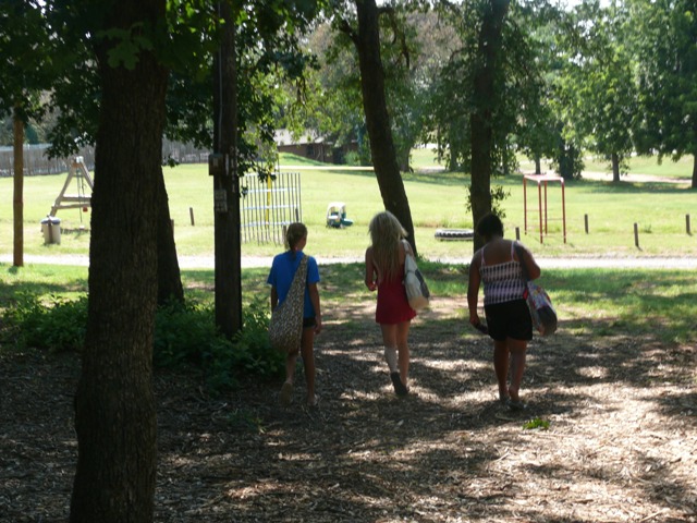 three people walking together near some trees in a park