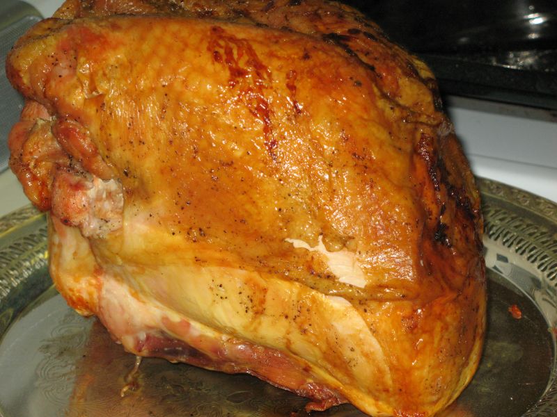 a ham on a metal pan being cooked