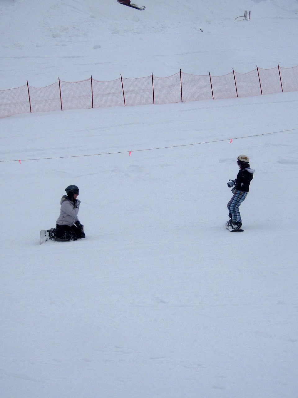 two people playing snowboard on a snowy slope