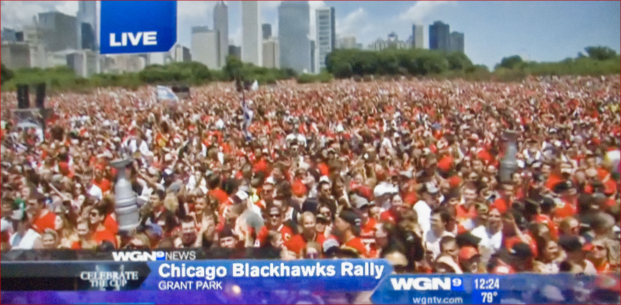 there are people standing and looking at the news on television