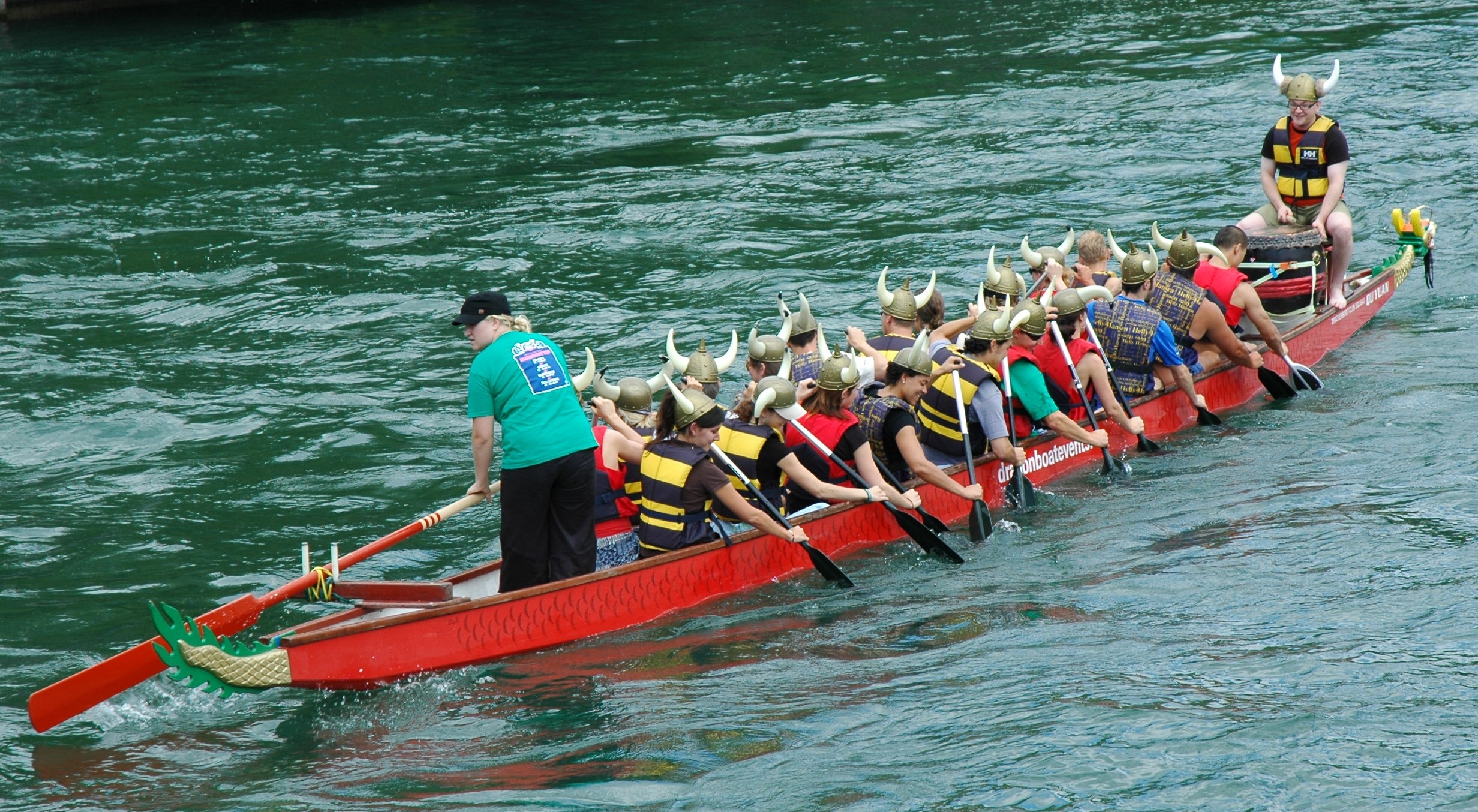 a man rowing a long boat with people in it