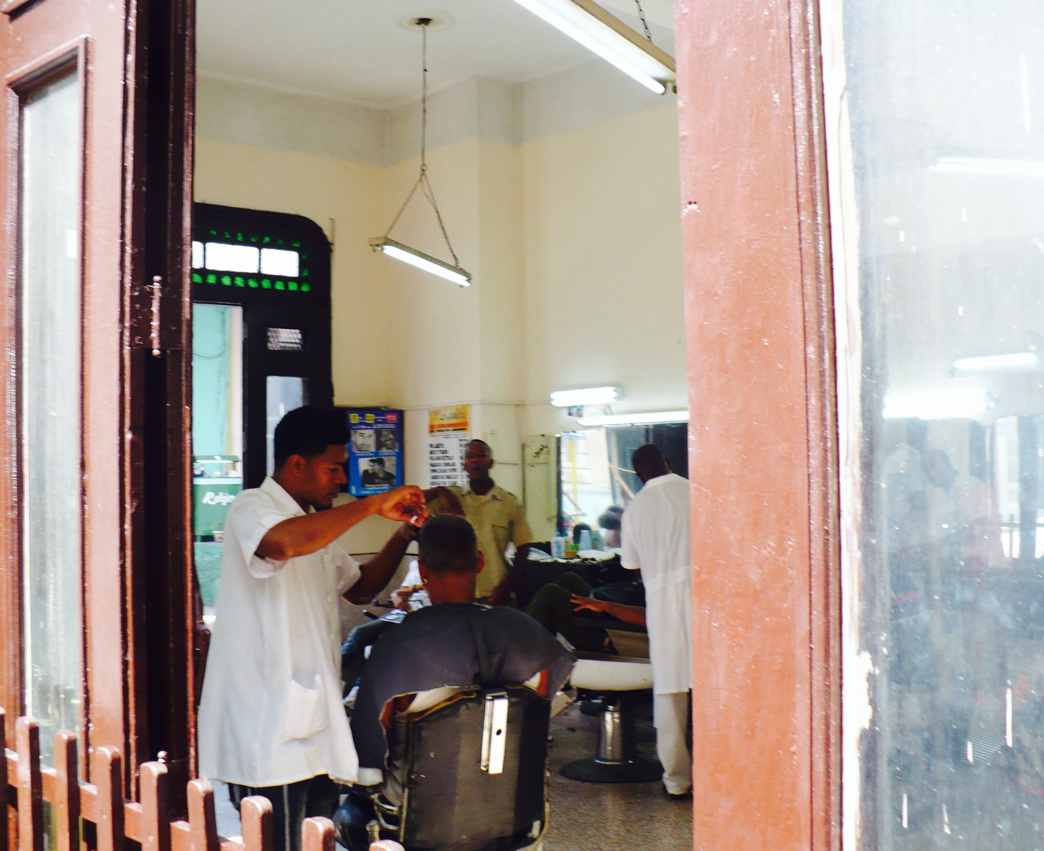 a barber shop getting his hair cut by two men