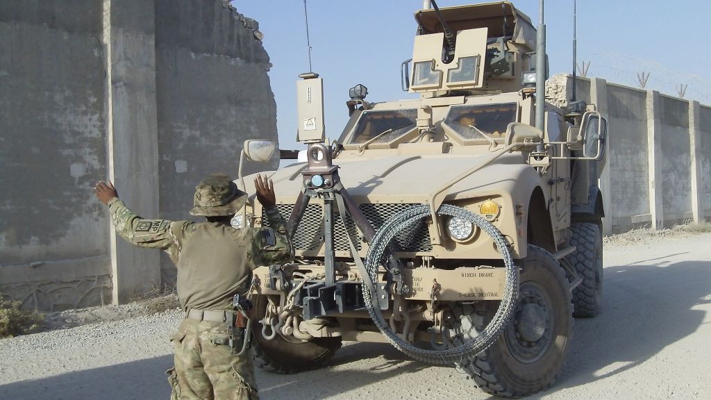 the soldier is next to the truck with the camera