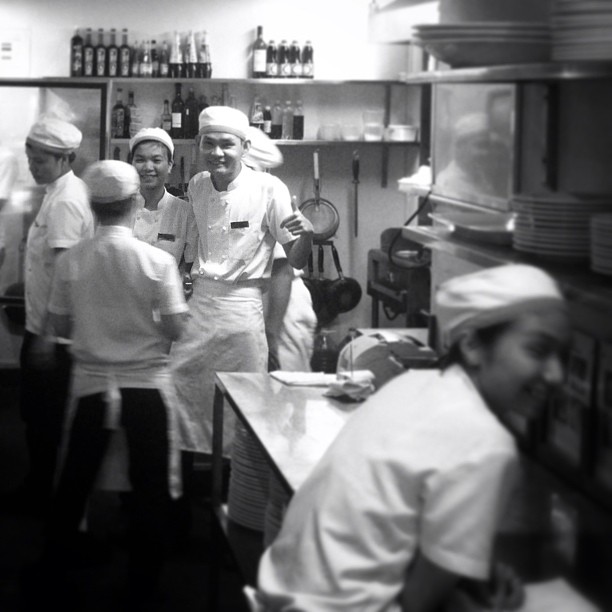 chefs and workers in a commercial kitchen preparing food