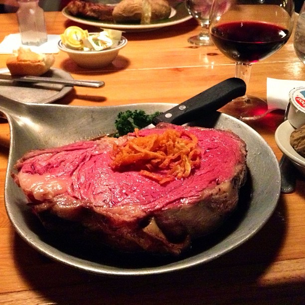 a steak in a serving bowl surrounded by other items