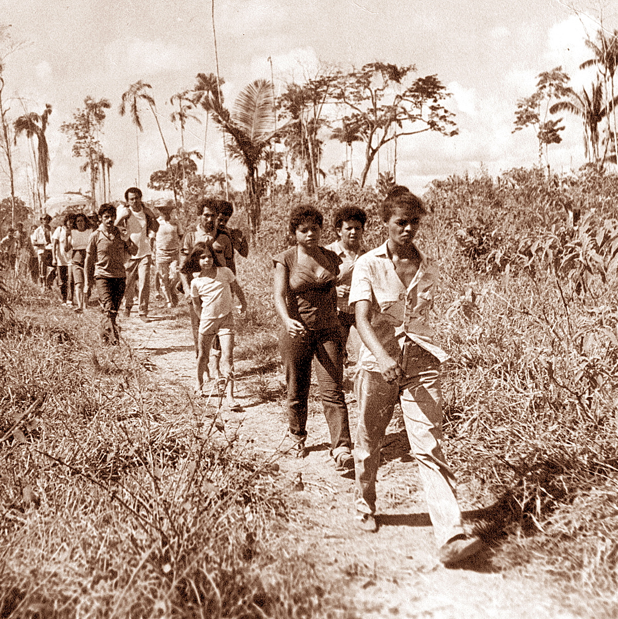 a group of s carrying baseball bats along a dirt path