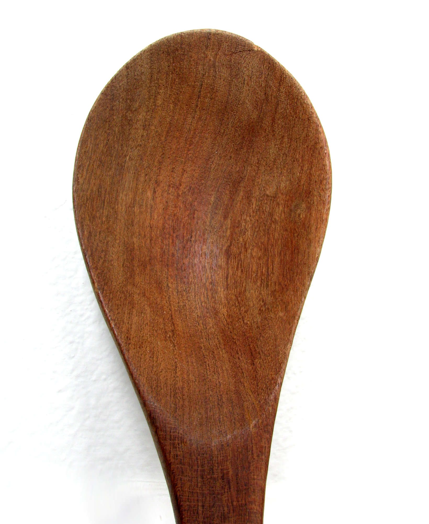 a close up of a wooden spoon on a white wall