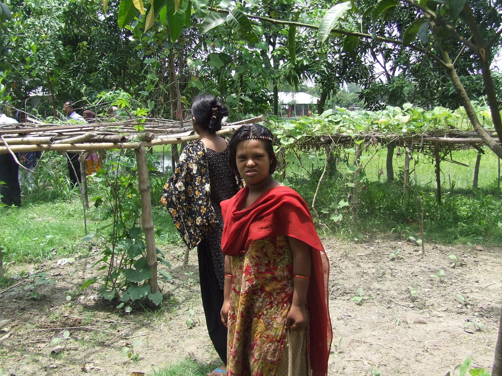 a woman in a red sari is standing behind an outdoor structure