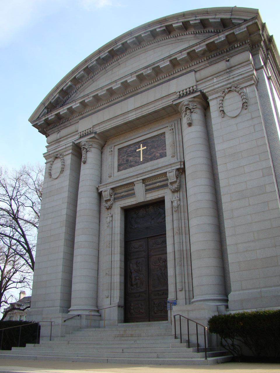 a very large white building with a clock and cross on the side