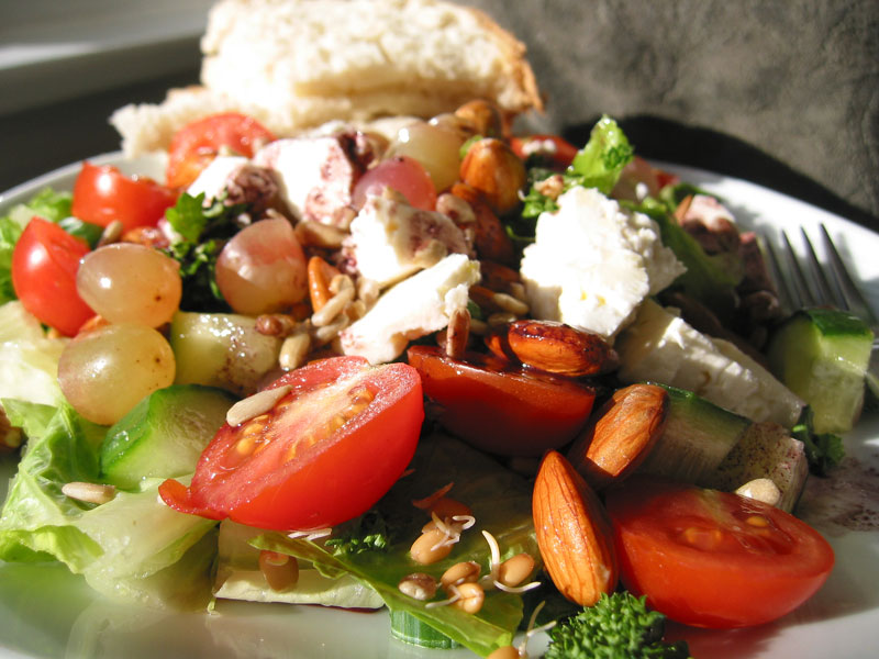 this is a close up picture of a salad with tomatoes, cheese and nuts