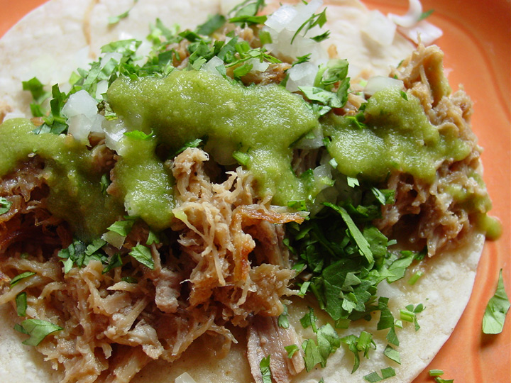 a tortilla filled with shredded meat covered in green sauce