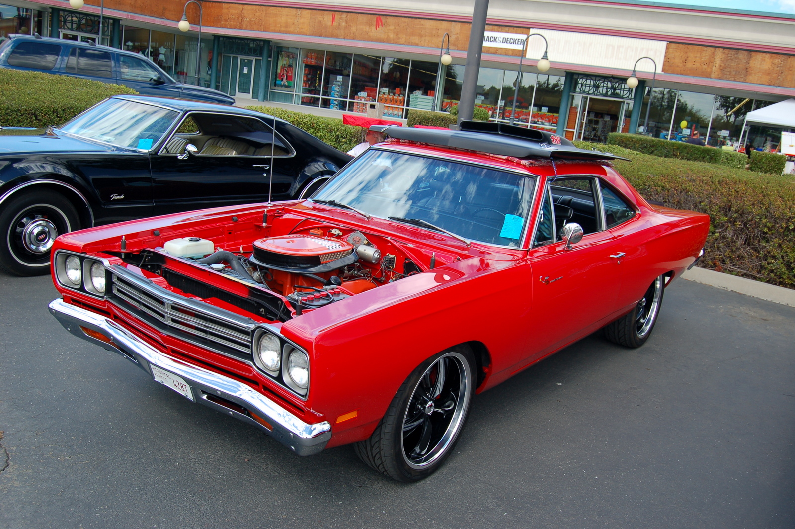 an older red car has its hood open