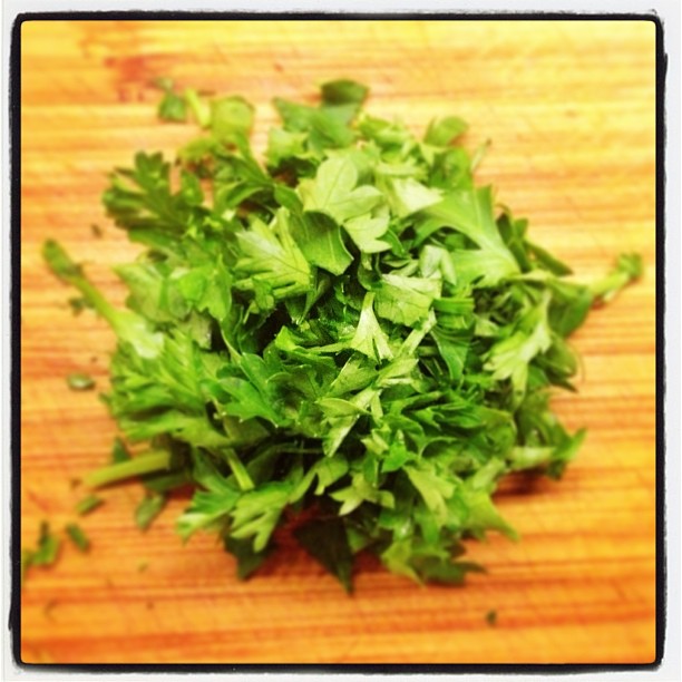 a pile of green leafy parsley sitting on top of a wooden surface