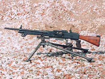 a machine gun and its arg sit on top of a gravel field