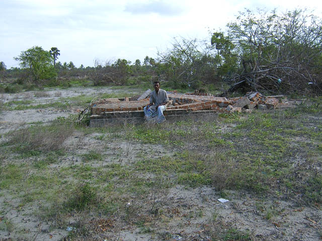 a man sitting on a pile of wooden pieces in a field