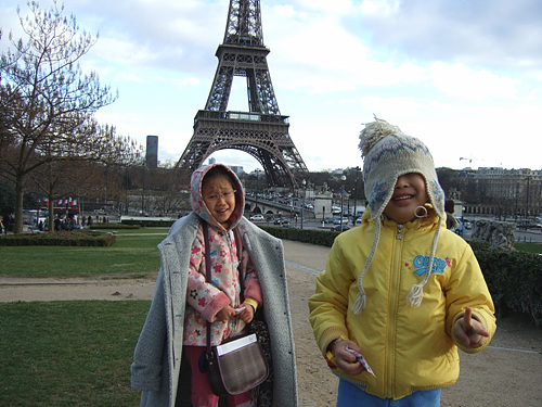 two women standing next to each other in front of the eiffel tower