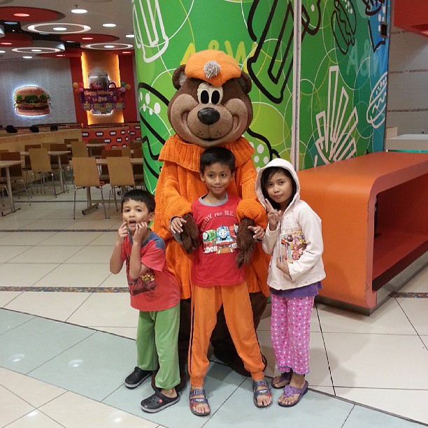 three children pose in front of an animal mascot