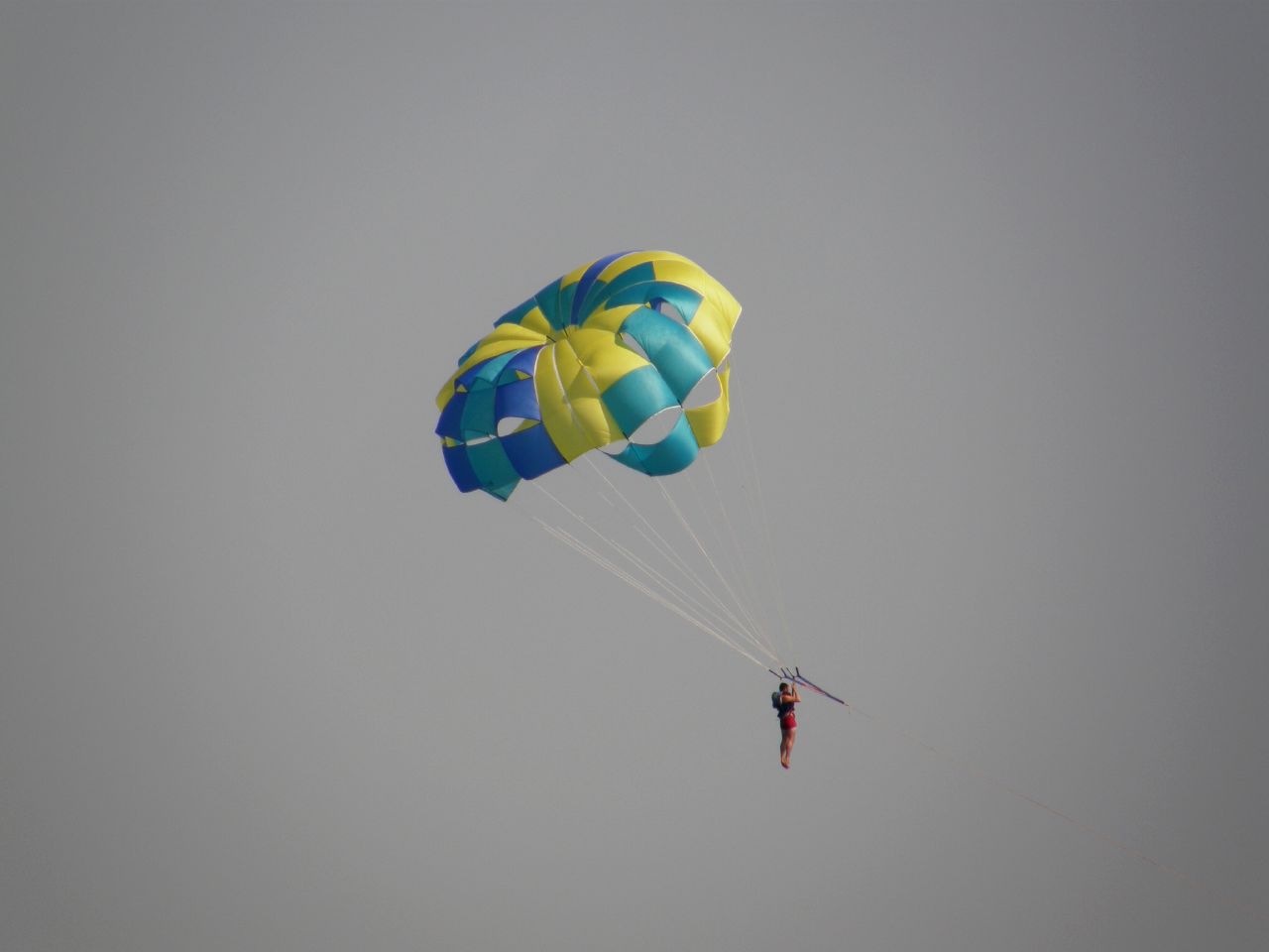 man in yellow parachute holding on to ropes