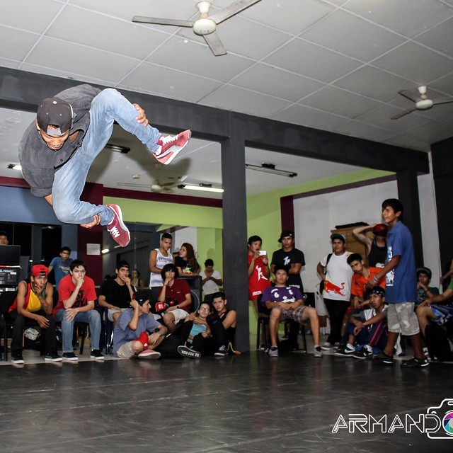 a boy does tricks with a skateboard while a crowd watches