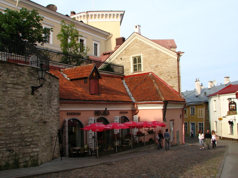 some buildings with tables and umbrellas in front