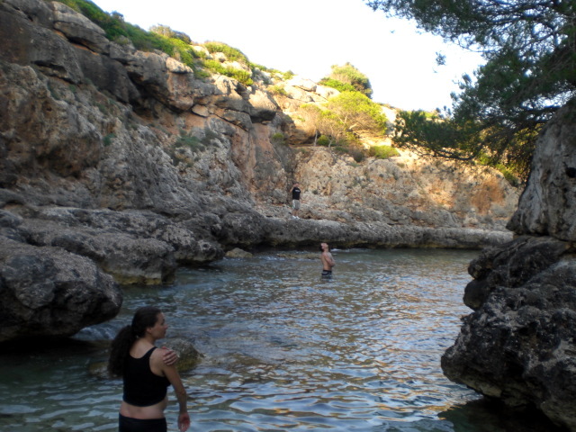 some people are standing in the water near some rocks