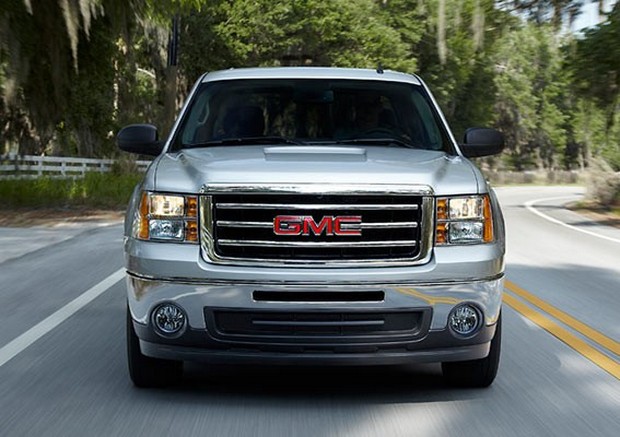 a silver gmc is driving down a road