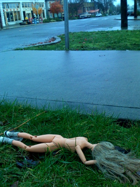 doll lying on the grass next to the curb