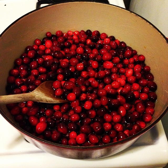 berries in a pan on the stove being cooked with a wooden spoon