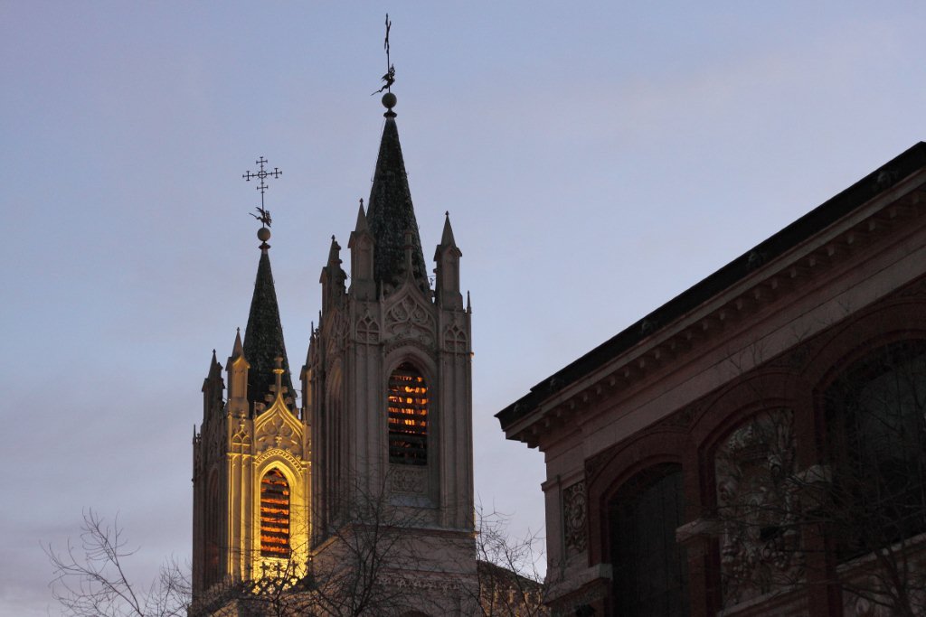 a tall church with many spires and lights at dusk