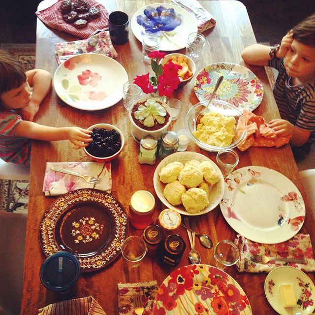 two children eating at a wooden table set for tea party